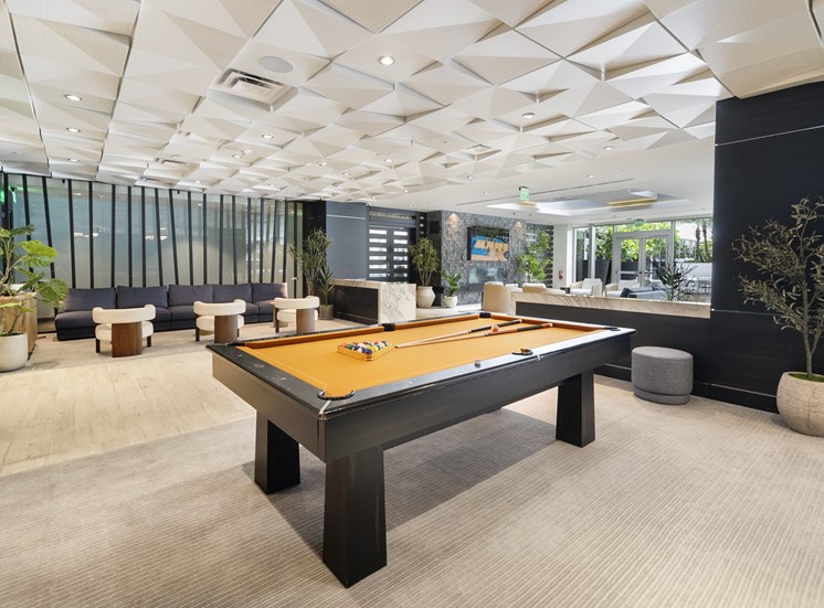 A pool table in a room with a black wall and a plant.
